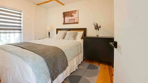 A bedroom with a bed, bedside table, lamp, and a framed picture on the wall. - Lake Cecebe Retreat #6- Maijac Resort & Marina (Burk`s Falls)