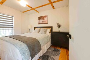 Ein Schlafzimmer mit Bett, Nachttisch, Lampe und einem gerahmten Bild an der Wand.