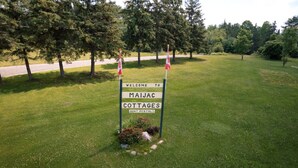 A welcome sign for Maijac Cottages with a flag and a small flower arrangement. - Lake Cecebe Retreat #6- Maijac Resort & Marina (Burk`s Falls)