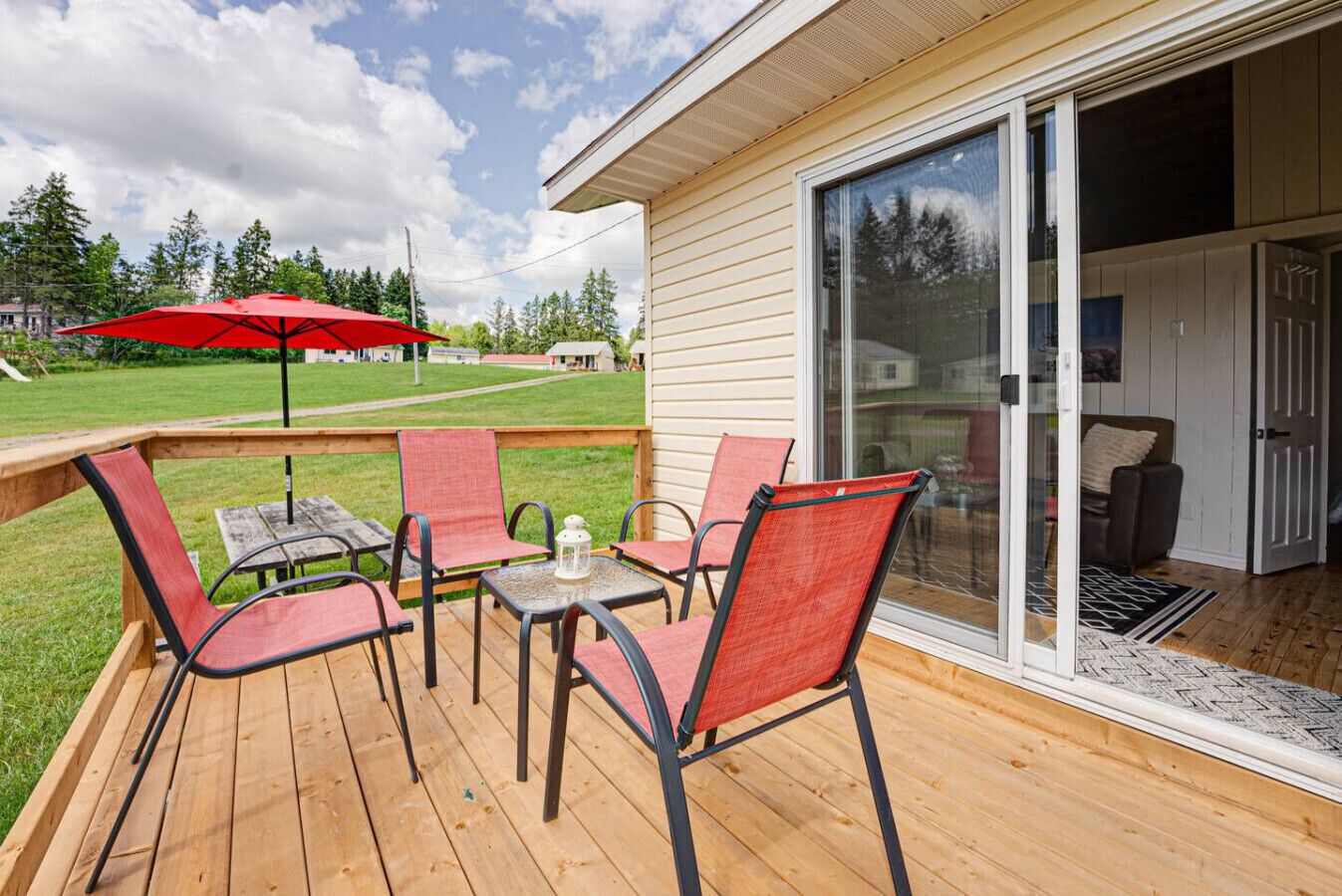 Une terrasse avec des meubles d’extérieur, un parasol rouge et une vue sur la maison.