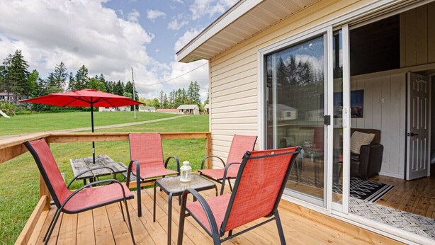 A deck with outdoor furniture, a red umbrella, and a view of the house. - Lake Cecebe Retreat #6- Maijac Resort & Marina (Burk`s Falls)