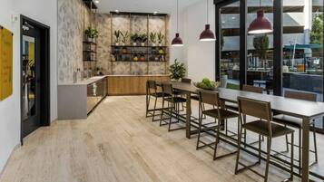 A modern kitchen with a wooden countertop, a built-in shelf with plants, and pendant lighting.