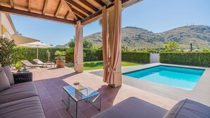 A covered outdoor area with a pool, lounge chairs, and a glass table. - Waterfront Port D'alcudia Villa for 8 (Alcúdia)