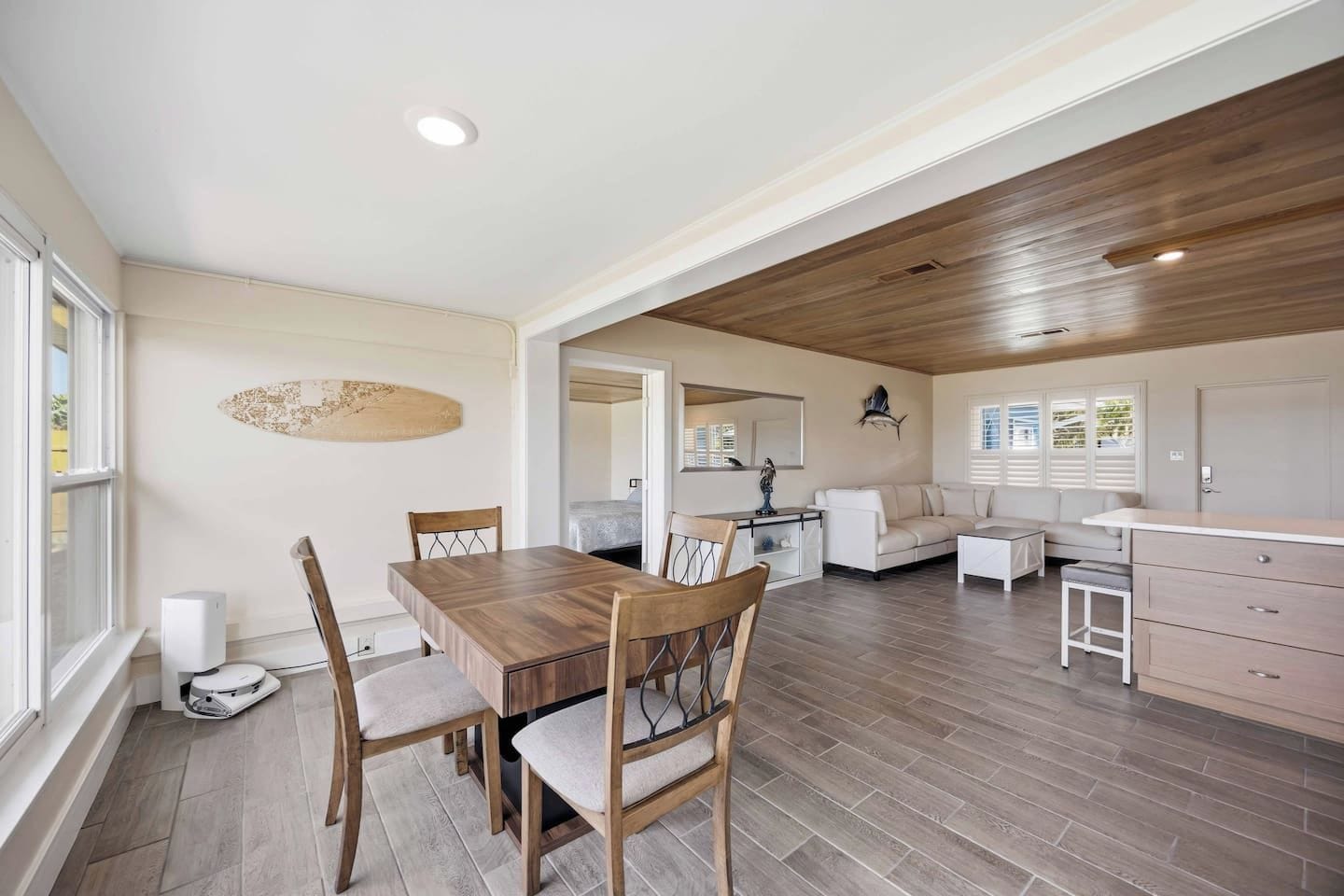 A spacious living area with a wooden dining table, chairs, a sofa, and a kitchenette.