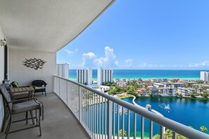Un balcon avec vue sur un port de plaisance, des immeubles et l’océan.