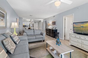 Un salon avec un canapé gris, une table basse et un téléviseur.