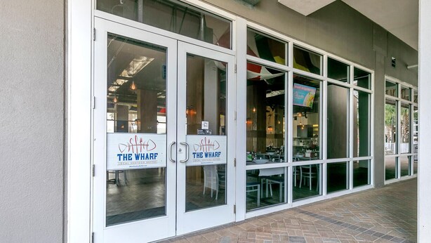 A restaurant with a sign reading "The Wharf" and a patio area with tables and chairs. - 🏖️Gulf Views-5 Pools-Laketown Wharf 1817🏖️ (Panama City Beach)