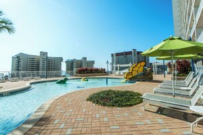 A swimming pool area with lounge chairs and umbrellas, surrounded by buildings. - 🏖️Gulf Views-5 Pools-Laketown Wharf 1817🏖️ (Panama City Beach)