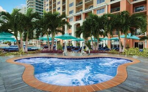 Ein Hotelpoolbereich mit Whirlpool, Liegestühlen und Sonnenschirmen.