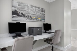 Un espacio de trabajo con dos monitores, una impresora y una silla.