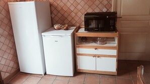 Ett kompakt kök med ett kylskåp, en mikrovågsugn och ett litet skåp med lådor.