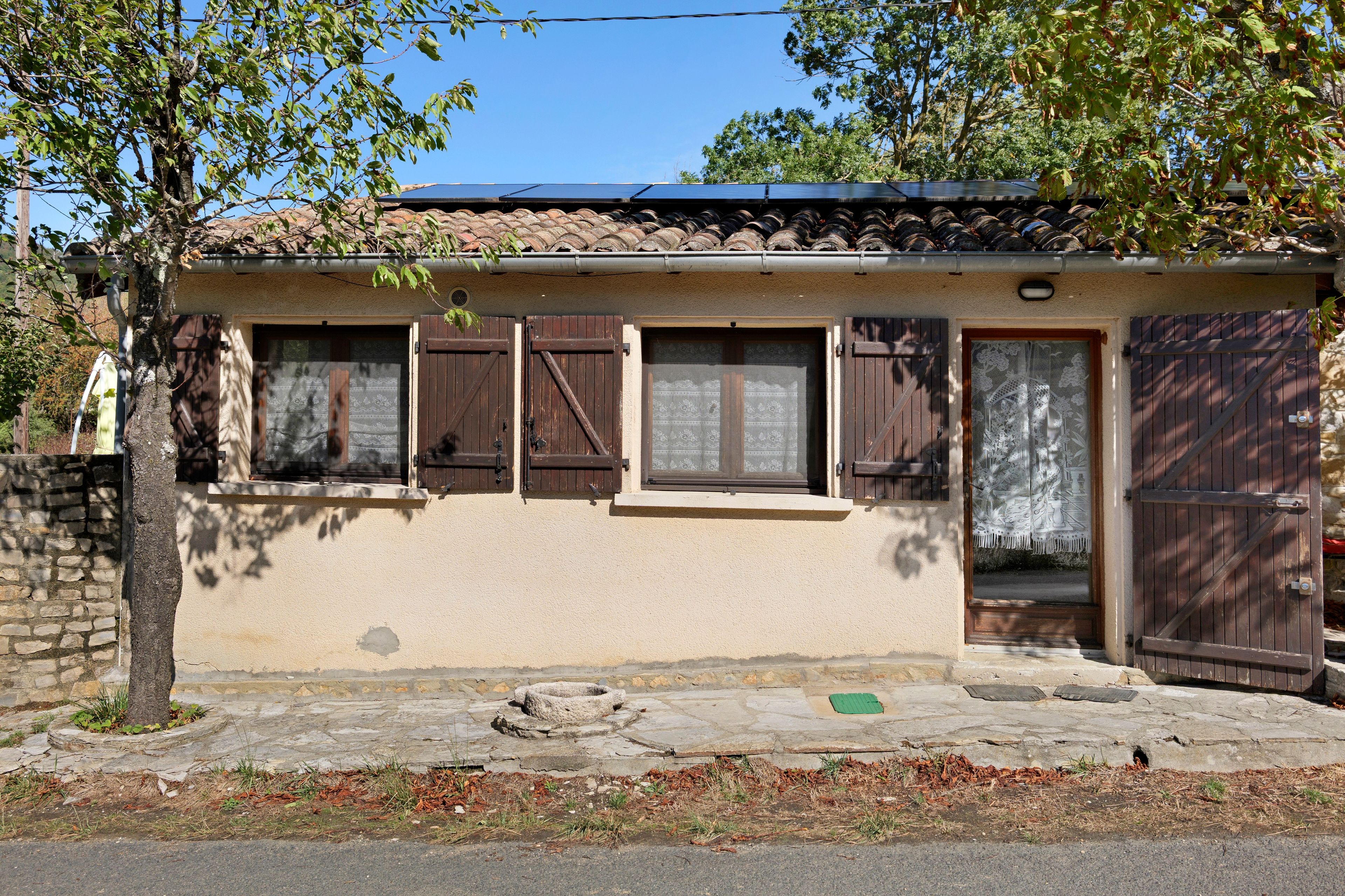 A building with a tiled roof, wooden shutters, and a stone foundation.