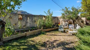 Un jardín con cerca de madera, una mesa con sillas y vistas a una montaña.