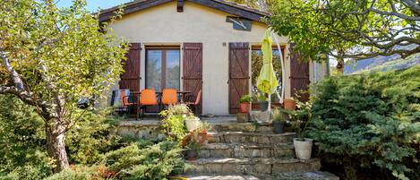 A house with a stone staircase leading to a porch with orange chairs and potted plants.