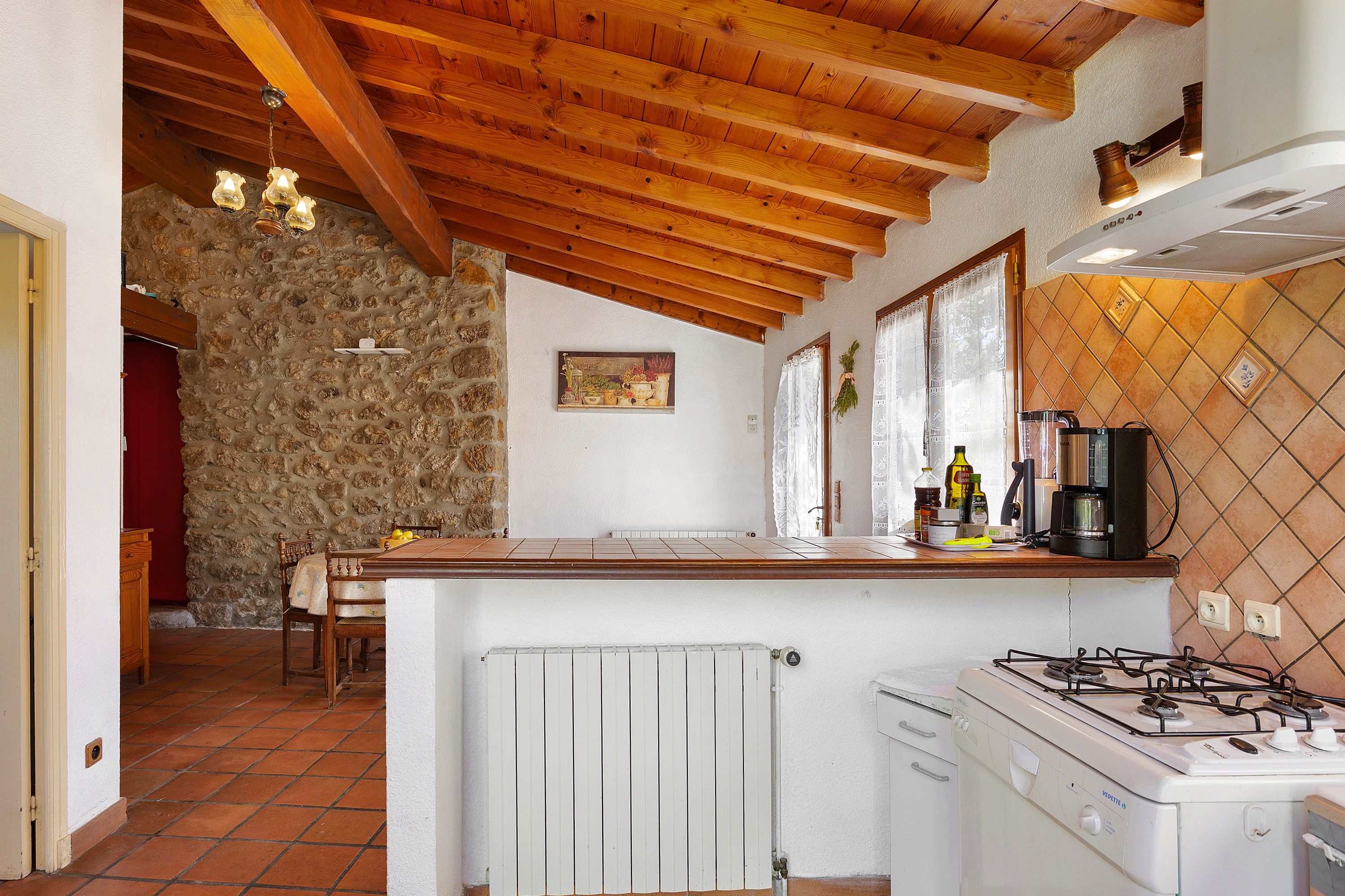 Une cuisine équipée d’une cuisinière à gaz, d’un réfrigérateur et d’un mur en pierre.