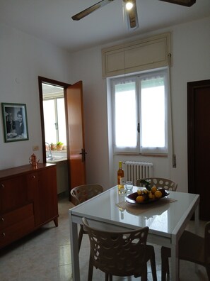 A dining area with a table, chairs, a radiator, a window, and a ceiling fan. - Spacious beachfront vacation home "LA TERRAZZA SUL MARE DI GALLIPOLI" 3274407527 (Gallipoli)