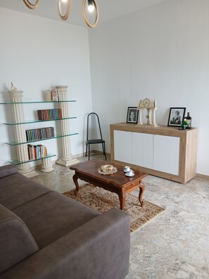 A living room with a brown sofa, a wooden coffee table, a glass bookcase, and a wooden cabinet with decorative items. - Spacious beachfront vacation home "LA TERRAZZA SUL MARE DI GALLIPOLI" 3274407527 (Gallipoli)