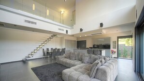A modern interior with a large sectional sofa, a staircase, and a kitchen area. - Exceptional 9-Bedroom Villa in Mougins (Mougins)