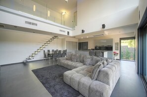 Ein modernes Interieur mit einem großen Ecksofa, einer Treppe und einer Küchenzeile.
