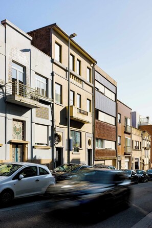 Ein mehrstöckiges Gebäude mit Balkonen, einer Garage und einer Straße mit parkenden Autos.