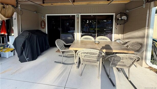 An outdoor patio with a table and chairs, a covered area with a fan, and a sliding glass door leading to the interior. - HUNTER SPRINGS condo with boat dock (Crystal River)