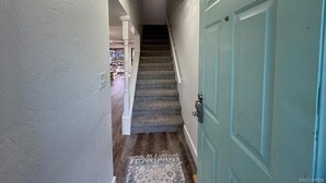 A hallway with a carpeted staircase leading to a door. - HUNTER SPRINGS condo with boat dock (Crystal River)