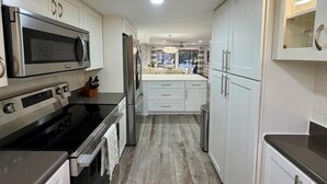 A modern kitchen with stainless steel appliances, white cabinetry, and a central island. - HUNTER SPRINGS condo with boat dock (Crystal River)