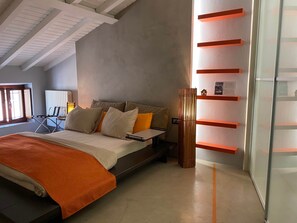 A modern bedroom with a bed, bedside table, and a tall, narrow decorative piece. - la terrazza sui tetti (Desenzano del Garda)