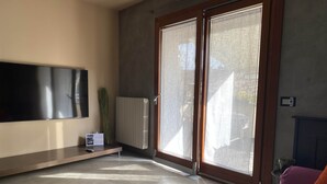 Ein modernes Wohnzimmer mit einem an der Wand befestigten Flachbildfernseher, einer Heizung und einem Sofa mit Kissen.
