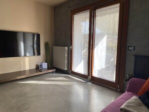 Ein modernes Wohnzimmer mit einem an der Wand befestigten Flachbildfernseher, einer Heizung und einem Sofa mit Kissen.
