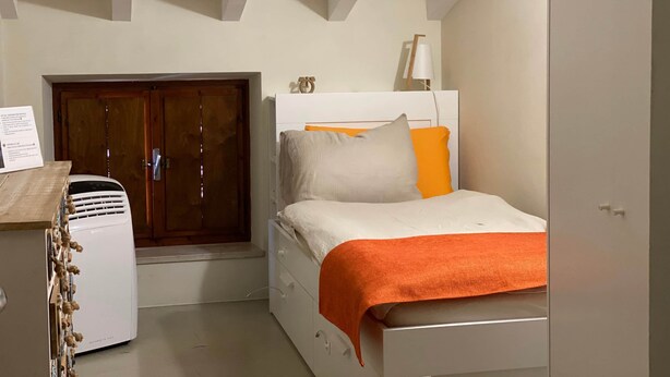 Ein Schlafzimmer mit Bett, Kleiderschrank, Heizung und Tür.