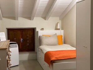 Une chambre à coucher avec un lit, une armoire, un radiateur et une porte.