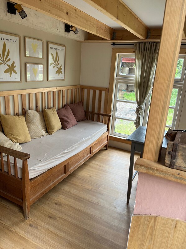 A cozy room with a wooden bench, a cushioned bench, and a window with curtains.