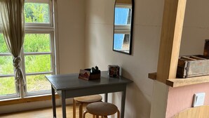 A room with a wooden table and two stools, a window with curtains, and a mirror on the wall. - Big Break in the Tiny House on the Farm Near the Baltic Sea (Schashagen)