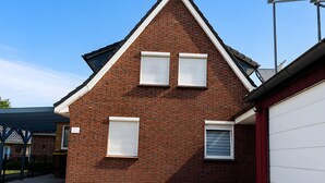 Ein Backsteinhaus mit einer Garagentür, zwei Fenstern mit Fensterläden und einem klaren Himmel.