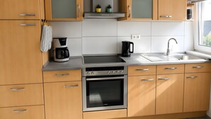 Eine moderne Küche mit Holzausstattung, integriertem Backofen, einer Kaffeemaschine und einem Spülbecken.