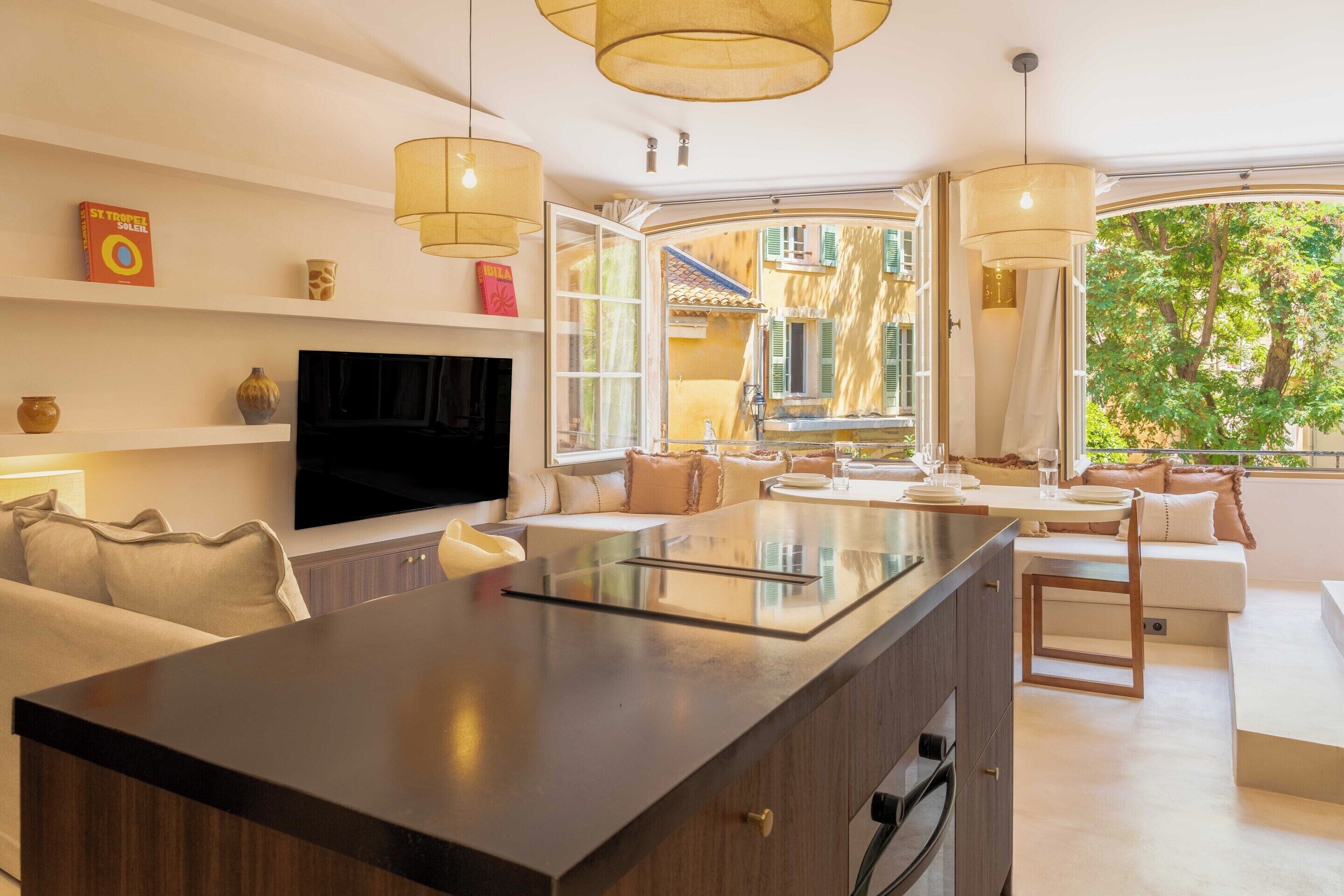 A modern kitchen with a central island, built-in appliances, and a large window offering a view of the outdoors.