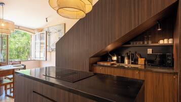 Una cocina moderna con acabados en madera oscura, una isla integrada y una lámpara colgante.