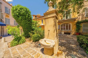 A cobblestone courtyard with a stone fountain, lush greenery, and traditional architecture. - Modern 2bdr Flat for 6P - Saint-tropez / Port (Saint-Tropez)