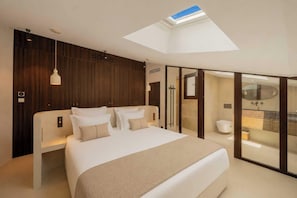 A modern bedroom with a skylight, a large bed with multiple pillows, a bedside table, and a view into the bathroom. - Modern 2bdr Flat for 6P - Saint-tropez / Port (Saint-Tropez)