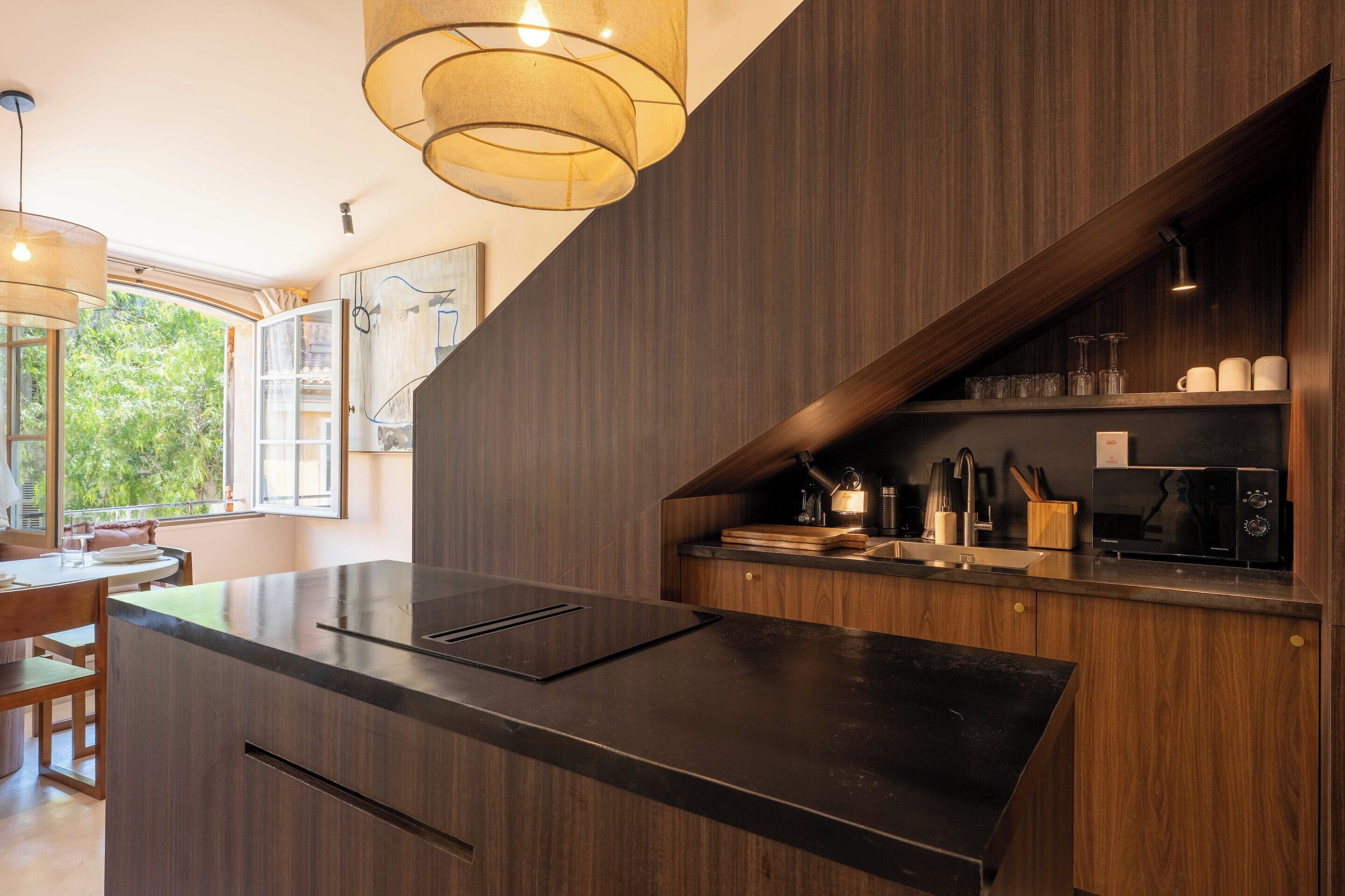 A modern kitchen with a dark wood finish, a built-in island, and a hanging light fixture.