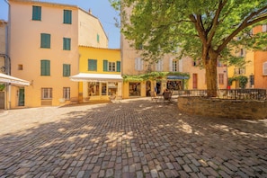 A cobblestone street with buildings, a tree, and outdoor seating. - Modern 2bdr Flat for 6P - Saint-tropez / Port (Saint-Tropez)