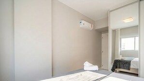 A hotel room with two beds, a large mirror, a window, and an air conditioning unit. - Apt. in Condo. w/ Pool & City View Pst1111 (Florianópolis)