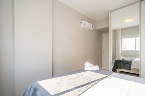 A hotel room with two beds, a large mirror, a window, and an air conditioning unit. - Apt. in Condo. w/ Pool & City View Pst1111 (Florianópolis)