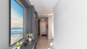 A hallway with a large window displaying a beach scene, a vase with flowers, and a modern light fixture. - Apartment in Condominium Near the Beach Pmr0501 (Porto Belo)