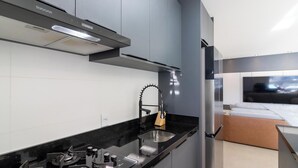 A modern kitchen with a stainless steel range, a built-in oven, and a black countertop. - Apartment in Condominium Near the Beach Pmr0501 (Porto Belo)