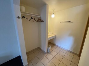 Baño con inodoro, lavamanos y toallero con ganchos.