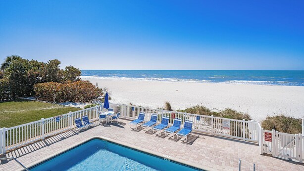 A pool area with lounge chairs and a view of the beach. - Oceanside 205-Private Balcony Sunsets (Indian Rocks Beach)