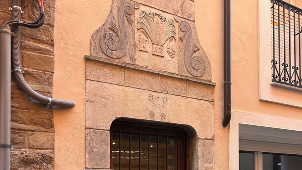 Fachada de edificio con puerta de madera, ventana con rejas de metal y pared de piedra.