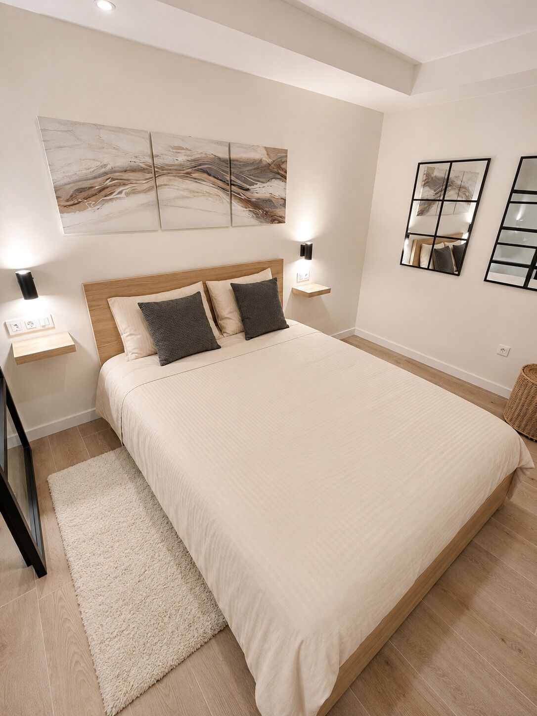 Un dormitorio con una cama grande, dos mesitas de noche, una mesilla auxiliar, una lámpara de pared y una lámpara de pie.